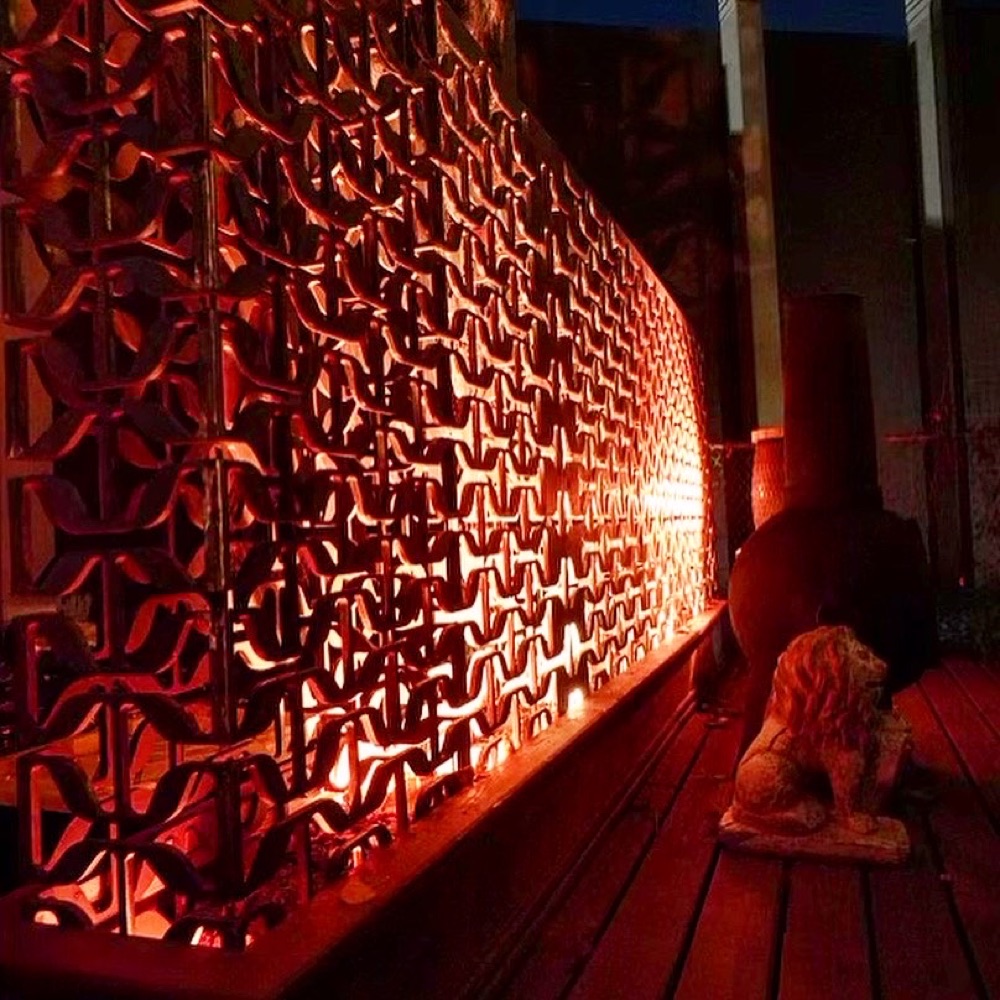 Salvaged-metal screen wall by Aaron Brand, lit warm at night