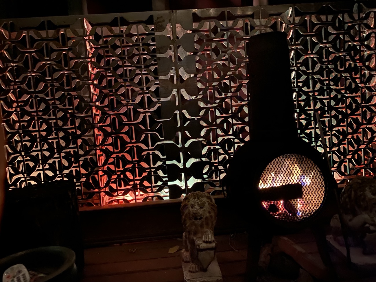 Metal screen wall backlit by a fire at night