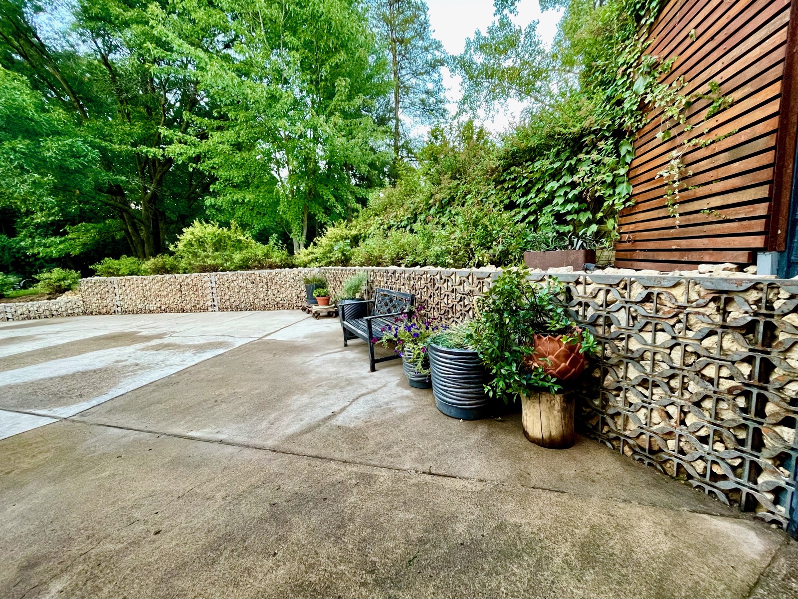 Backyard patio framed by gabion stone-and-metal walls