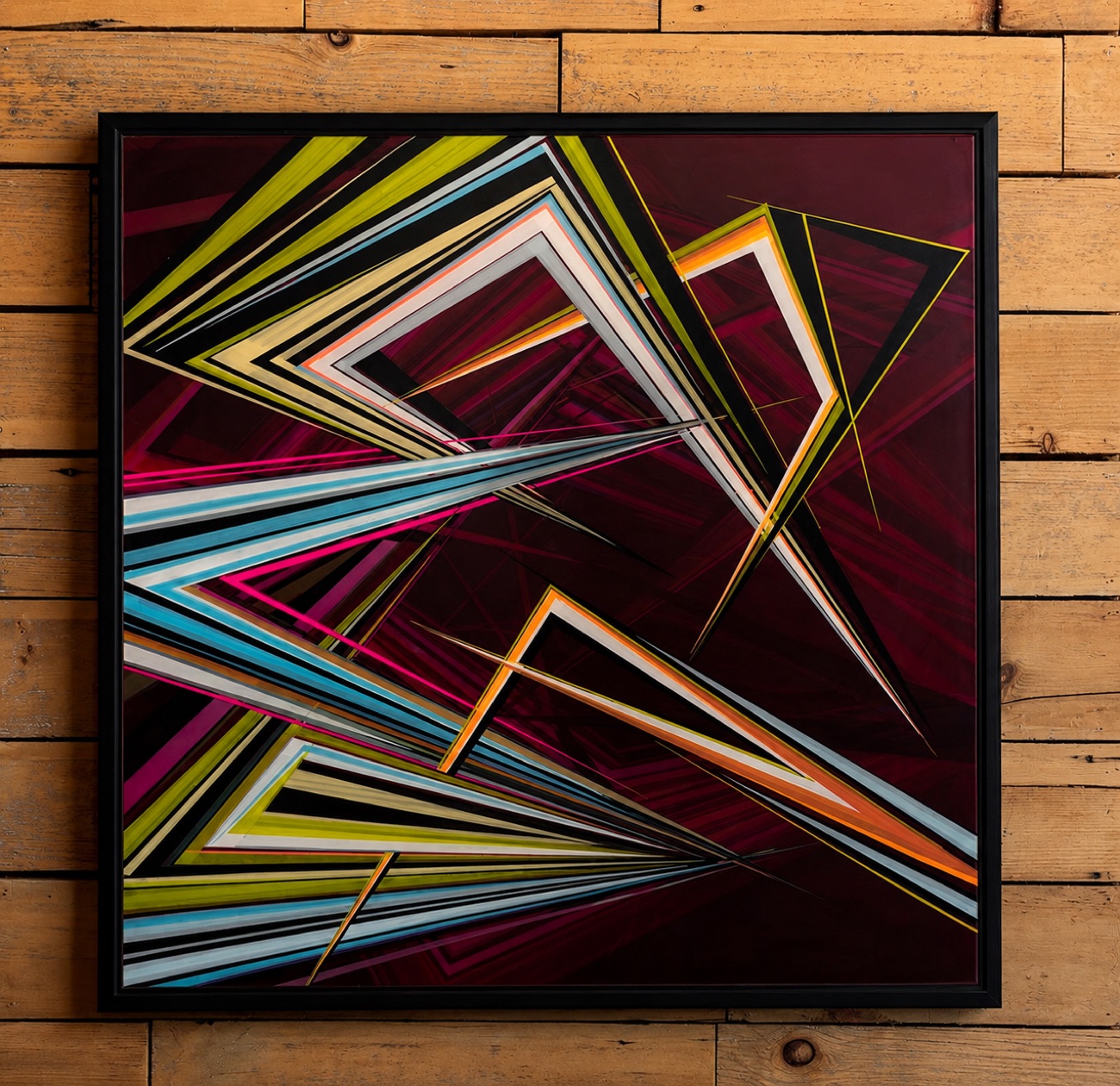 Framed geometric painting, bright angular bands over a deep maroon field