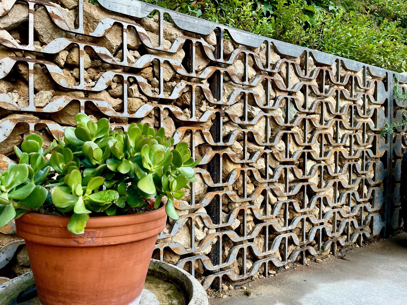 Salvaged mid-century metal screen over a stone gabion wall